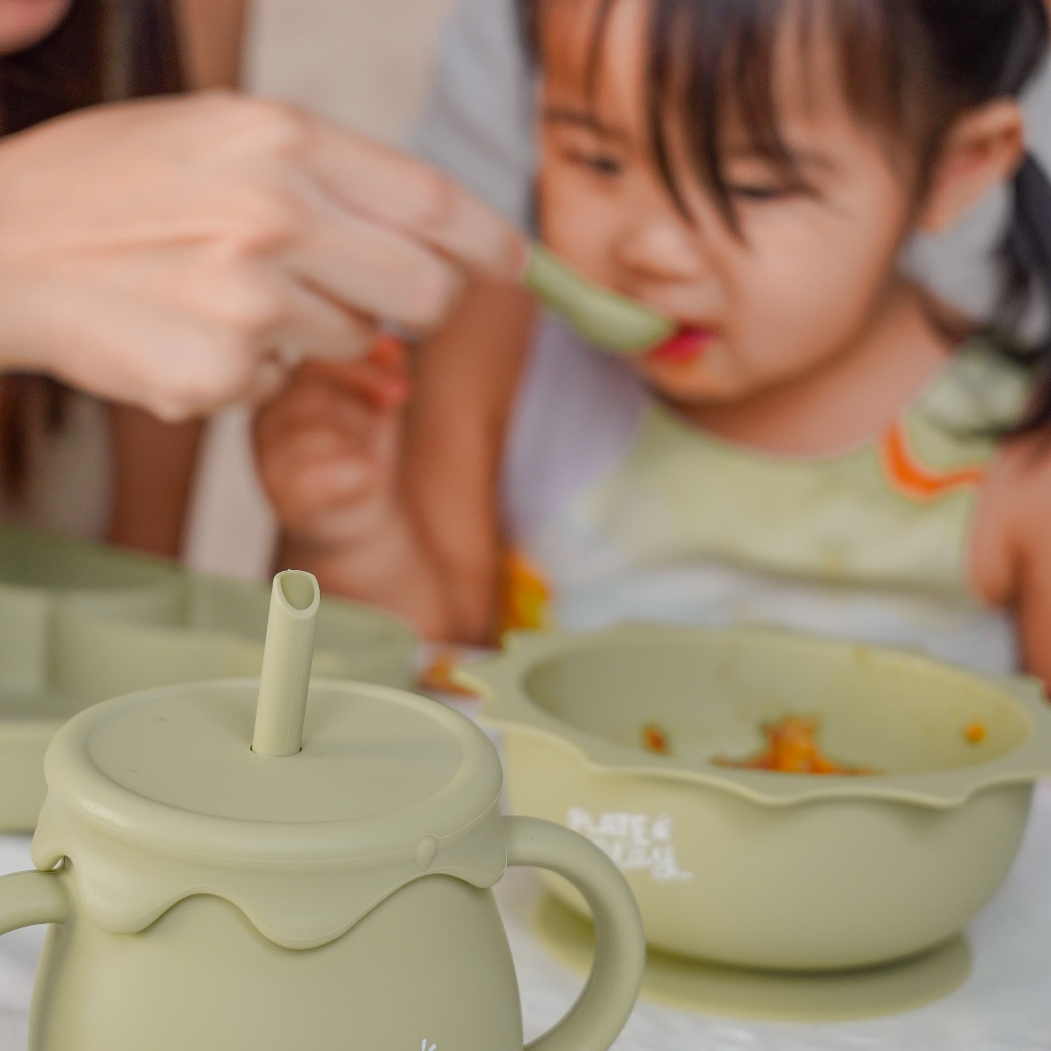 Toddler tasting a meal with a Plate and Play bowl and cup